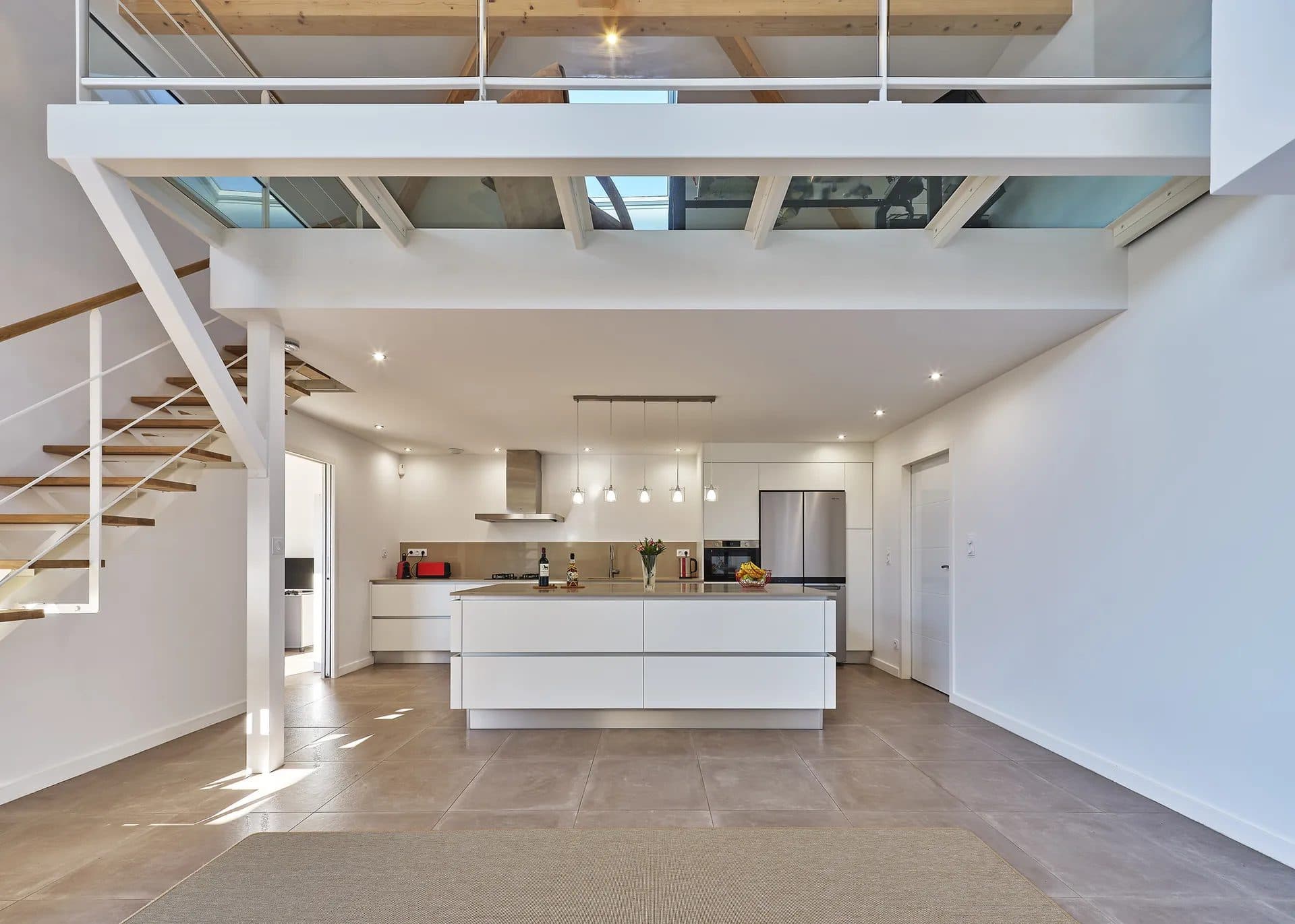 Double hauteur avec mezzanine, escalier métallique blanc et cuisine ouverte