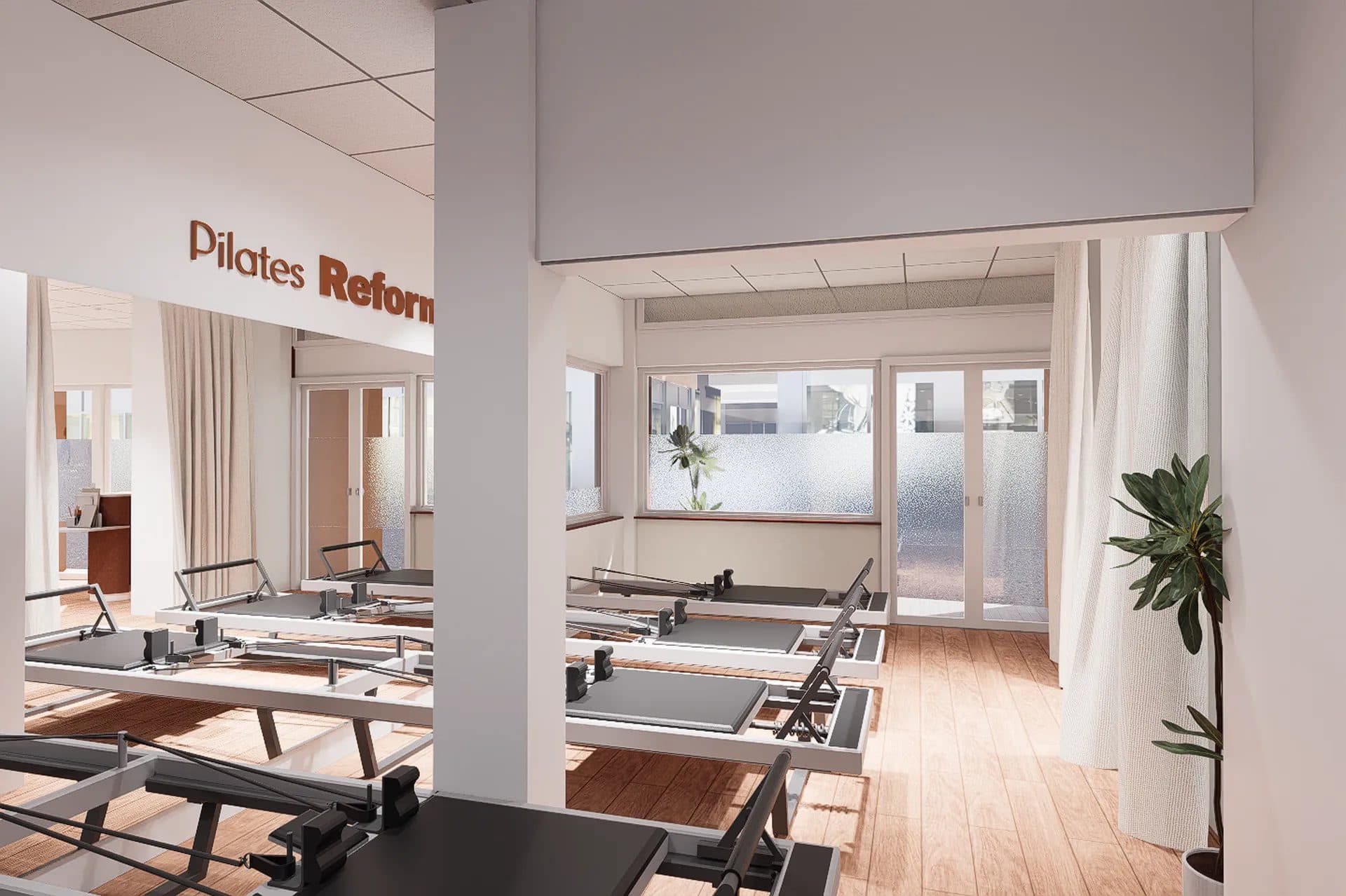 Salle de Pilates avec appareils Reformer alignés, parquet clair et grande baie