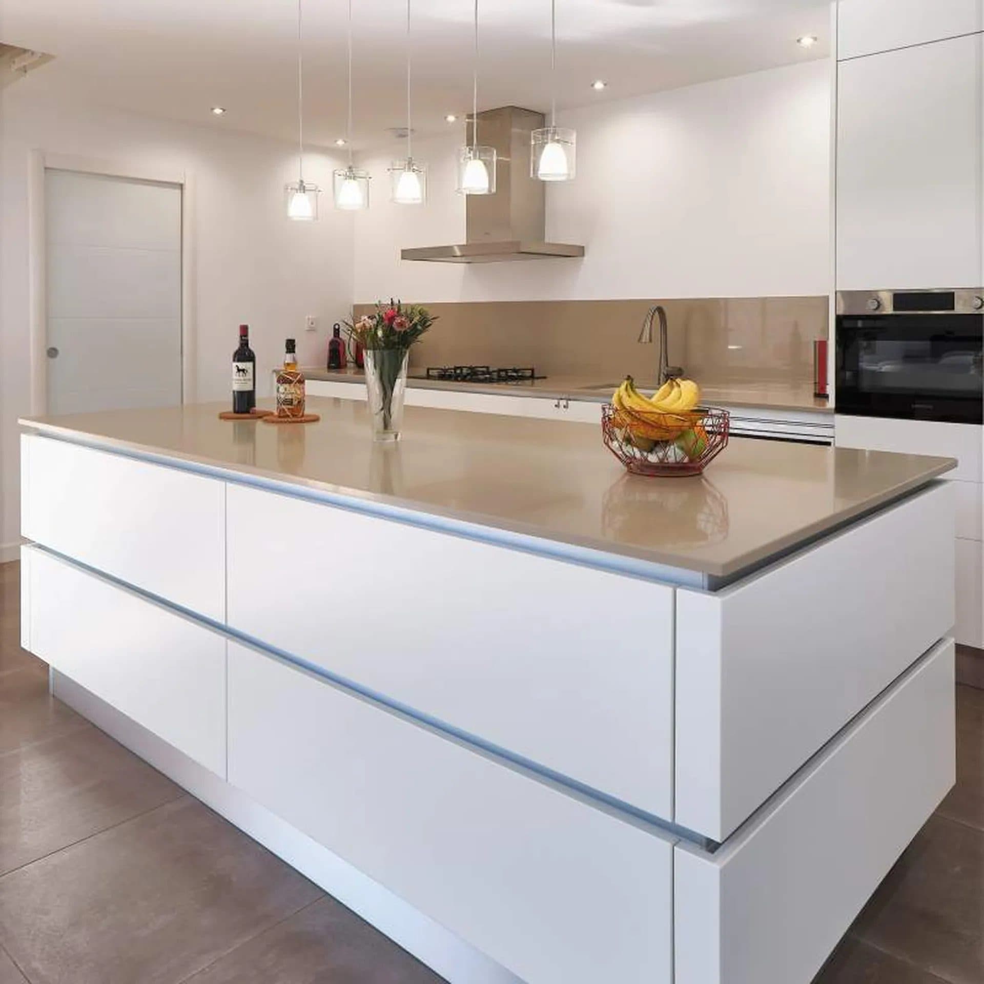 Îlot de cuisine blanc toute longueur, hotte suspendue et sol en grand carrelage