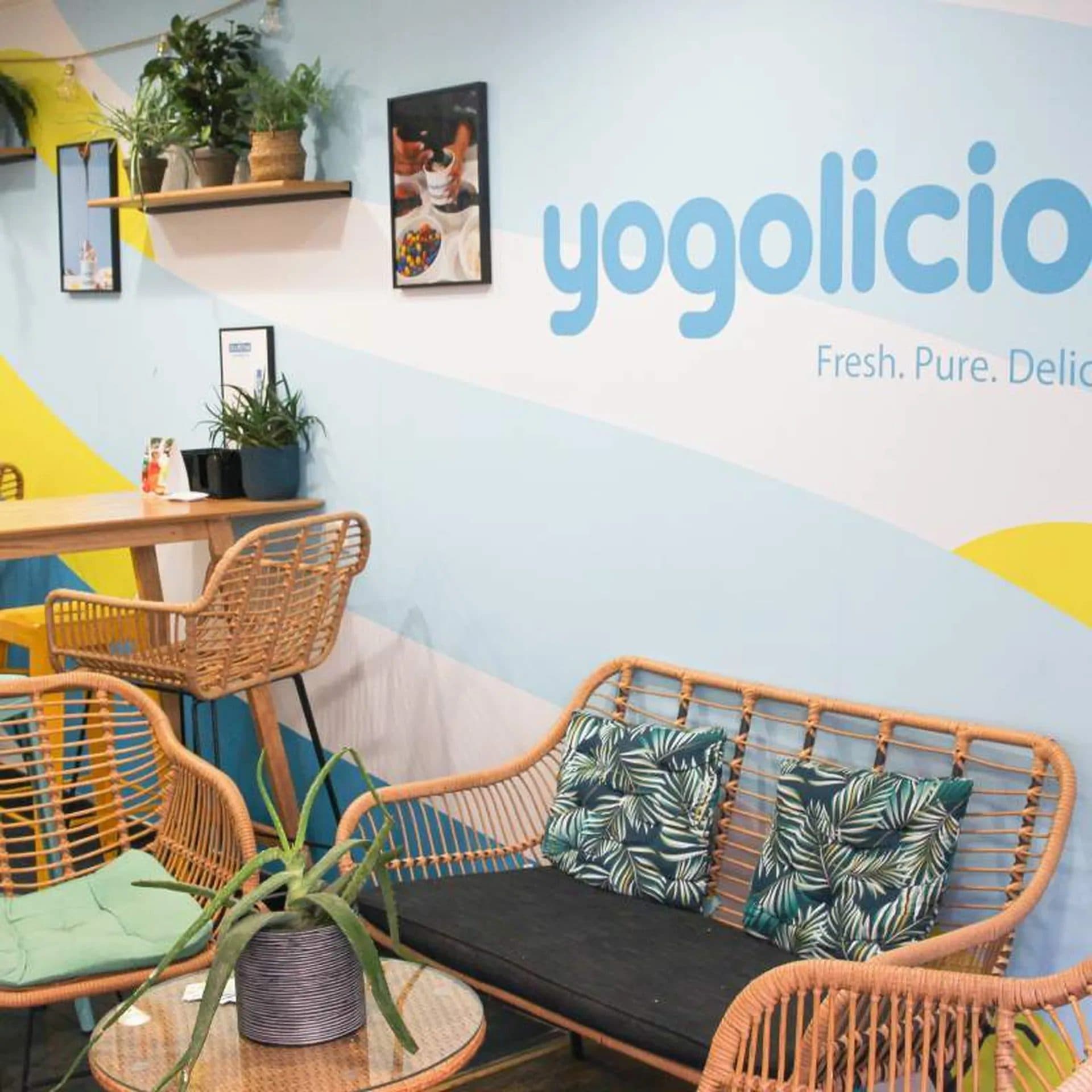 Salle de la boutique avec fresque murale colorée, banquette en rotin et coussins tropicaux